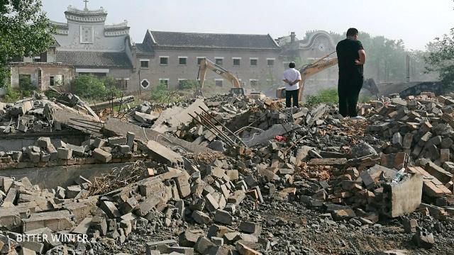 教会の正面口を取り壊す2台の掘削機